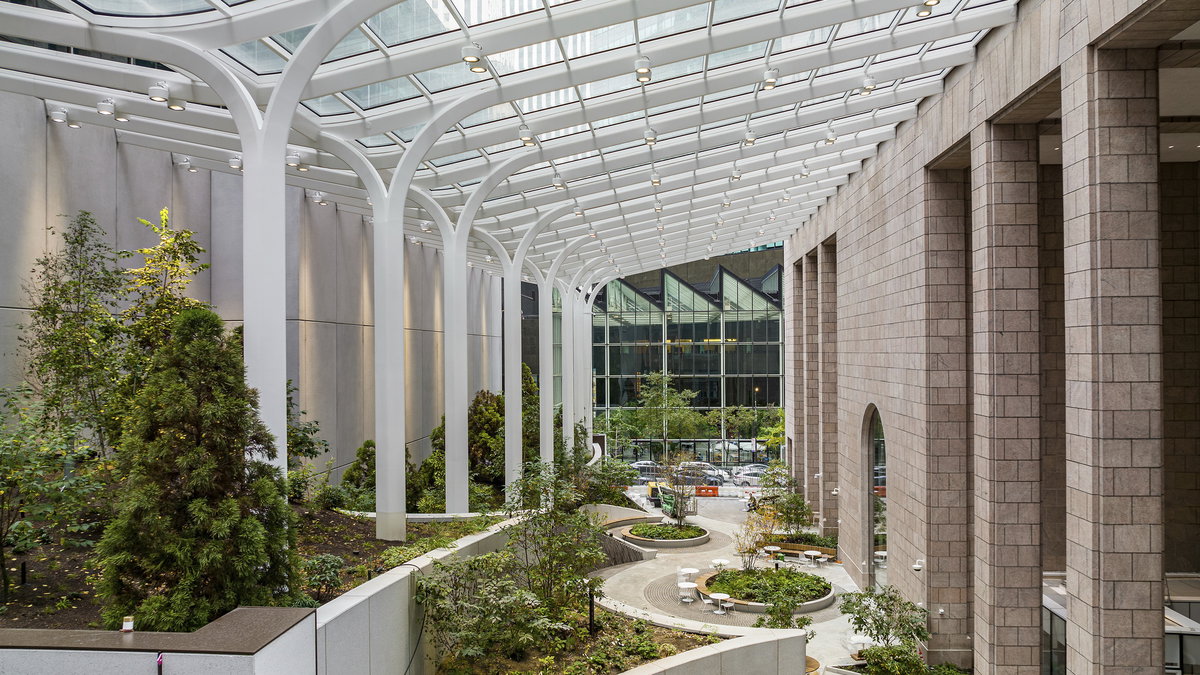 Light-filled planted interior atrium beneath a glazed canopy at 550 Madison Avenue